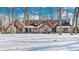Brick home with snow-covered lawn, nestled among tall trees at 7425 Cherryhill Dr, Indianapolis, IN 46254