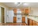 Galley kitchen with wood cabinets, white appliances, and mosaic backsplash at 2716 Redland Ln, Indianapolis, IN 46217