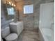 Modern bathroom with grey tile, white vanity, and a bathtub at 3305 E 30Th St, Indianapolis, IN 46218