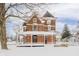 Brick two-story house with a wraparound porch, sitting on a snow-covered lot at 503 S Harrison St, Alexandria, IN 46001