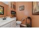 Small bathroom with orange walls, pedestal sink, and decorative accents at 6023 Twyckenham Dr, Indianapolis, IN 46236