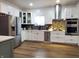 The kitchen features ample white cabinetry, stainless steel appliances, and an island with seating at 3156 Graceland Ave, Indianapolis, IN 46208