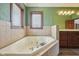 Large tiled bathtub next to a bright window within a green walled bathroom at 9263 Compton Farm Ln, Indianapolis, IN 46259
