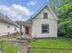 Charming home with a red front door and light colored siding surrounded by a metal fence and some plants at 1819 Southeastern Ave, Indianapolis, IN 46201