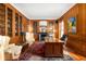 Wood-paneled office featuring built-in bookshelves, a fireplace, and a large wooden desk at 4601 N Legacy Dr, Muncie, IN 47304