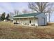 Exterior view of a spacious barn with a white exterior, green roof, and open patio at 5682 N Michigan Rd, Fairland, IN 46126