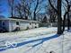 A spacious backyard with a grey house, tall trees, and a light dusting of snow at 4818 E 14Th St, Indianapolis, IN 46201
