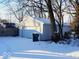 Detached two-car garage with white doors and gray siding, with a snow covered driveway at 4818 E 14Th St, Indianapolis, IN 46201