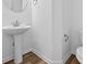 Elegant powder room features pedestal sink, stylish fixtures, and wood-look flooring for a touch of modern charm at 5123 Rolling Meadow Blvd, Indianapolis, IN 46237