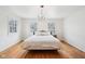 Bright bedroom with hardwood floors, a queen-sized bed, chandelier, and natural light from two windows at 7830 Ridgeland Dr, Indianapolis, IN 46250