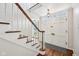 Bright foyer with hardwood floors, white staircase, and classic front door at 7830 Ridgeland Dr, Indianapolis, IN 46250