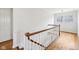 Bright hallway staircase with hardwood floors, white walls, and wood railing leading to a well-lit landing at 7830 Ridgeland Dr, Indianapolis, IN 46250