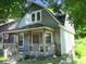 Cozy home with a covered front porch, mature trees, and a neatly landscaped front yard at 1138 W 33Rd St, Indianapolis, IN 46208