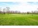 Expansive green field surrounded by trees under a bright sky offers versatile outdoor space at 2940 Washington St, Columbus, IN 47201