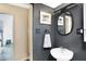 Modern bathroom with dark walls, pedestal sink, and oval mirror at 3965 N Meridian St # Apt 6C, Indianapolis, IN 46208