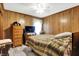 Bedroom with wood paneled walls, hardwood floors, and a dresser at 457 S High School Rd, Indianapolis, IN 46241