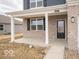 Charming front porch featuring white columns, brick facade, a black door, and a well-manicured lawn at 6039 Granby Dr, Whitestown, IN 46075