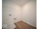 Compact laundry room featuring wood-look floors, wire shelving, and utility connections at 6039 Granby Dr, Whitestown, IN 46075