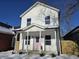 Two-story white house with pink door, covered porch, and snow-covered yard at 1306 E Minnesota St, Indianapolis, IN 46203