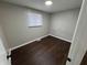 Simple bedroom with dark brown flooring and a window with blinds at 1801 W Morris St, Indianapolis, IN 46221