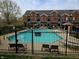 Community pool with lounge chairs and umbrellas surrounded by manicured landscaping and wrought iron fence at 6595 Reserve Dr, Indianapolis, IN 46220