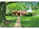 Charming home with lush green lawn, mature tree, and welcoming walkway to the front door at 6072 Meridian St W Dr, Indianapolis, IN 46208