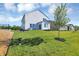 Manicured backyard showcasing a lush lawn, complemented by a modern white home and vibrant green tree at 5107 Maddox Ln, Whitestown, IN 46075