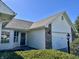 Exterior view features a two-car garage, brick accents, and neatly trimmed green bushes in front of home at 6615 Rushing, Noblesville, IN 46062