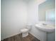 Bathroom featuring a pedestal sink, toilet, and light gray wood-look floors at 8798 Walker St, Fortville, IN 46040