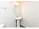 Bathroom featuring a white pedestal sink, oval mirror, and modern lighting at 9217 Hawley Dr, Indianapolis, IN 46216