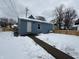 Rear view of a blue house with a snow-covered yard and wooden fence at 1256 Kappes St, Indianapolis, IN 46221