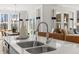 Kitchen island boasts barstool seating, double sinks, and modern fixtures with a view to the dining and living spaces at 19349 Sumrall Pl, Westfield, IN 46074