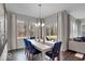 Bright dining area with view to backyard through multiple windows and door, modern chandelier, white table, bench, and chairs at 19365 Sumrall Pl, Westfield, IN 46074