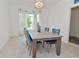 Bright dining room with wood table, chandelier, and blue upholstered chairs near a window at 4061 Omaha Dr, Bargersville, IN 46106