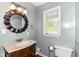 This well-lit bathroom features a traditional vanity, round mirror, and window offering plenty of natural light at 475 Golf Ln, Indianapolis, IN 46260