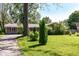 A single-story brick home with lush green lawn and mature trees under a blue sky, creating a serene setting at 475 Golf Ln, Indianapolis, IN 46260