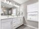Bathroom with double sink vanity, white cabinets, a large mirror, and a window providing outdoor views at 5442 W Turnbuckle Pl, McCordsville, IN 46055