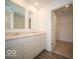 Bright bathroom featuring double sinks, quartz countertops, and wood-look flooring at 6618 Sulgrove Pl, Indianapolis, IN 46221