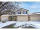 Charming townhouse with a two-car garage, brick accents, and snow-covered landscaping at 7218 Forrester Ln, Indianapolis, IN 46217