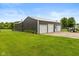 Large outbuilding featuring three garage doors, situated on a well-maintained lawn at 7775 N Kitchen Rd, Mooresville, IN 46158