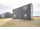 Rear exterior view of a home with dark siding, a concrete patio, and a neutral lawn at 7872 Magnolia St, New Palestine, IN 46163