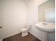 Compact half-bathroom featuring a white pedestal sink, toilet, and a large mirror on a clean white wall at 7872 Magnolia St, New Palestine, IN 46163