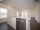 Kitchen island with stainless steel dishwasher and sink, white countertop, and view of other rooms in the house at 7872 Magnolia St, New Palestine, IN 46163