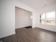 Living room featuring white walls, dark wood-look flooring, and abundant natural light from a large window at 7872 Magnolia St, New Palestine, IN 46163