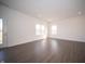 Spacious living room featuring an exterior door and windows with white trim and dark floors at 7872 Magnolia St, New Palestine, IN 46163
