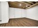 Finished basement with exposed beams, white brick, and wood flooring at 1656 Roosevelt Ave, Indianapolis, IN 46218