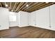 Finished basement with exposed beams, white brick, and wood flooring at 1656 Roosevelt Ave, Indianapolis, IN 46218