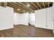 Finished basement with exposed beams, white brick, and wood flooring at 1656 Roosevelt Ave, Indianapolis, IN 46218