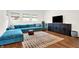 Open living area with teal sectional sofa, wood floors, and a large TV at 1656 Roosevelt Ave, Indianapolis, IN 46218