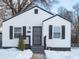 White house with black shutters, gray door, and snowy yard at 3501 Caroline Ave, Indianapolis, IN 46218
